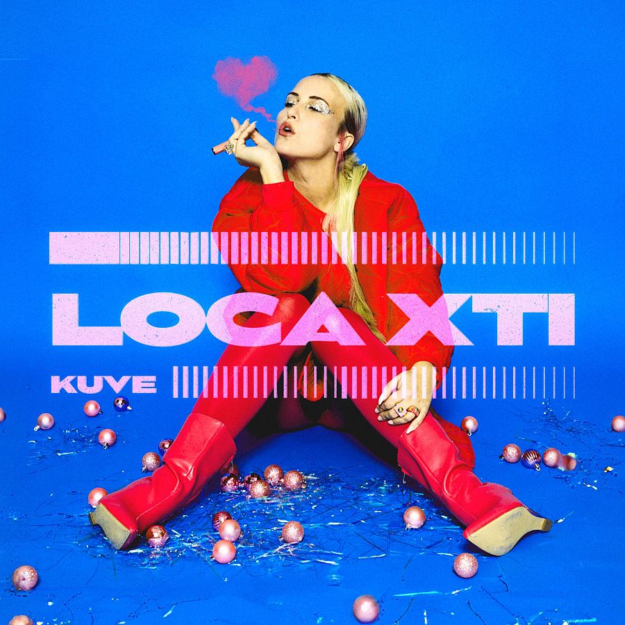 Kuve en la portada de su canción "LOCA X TI" para Benidorm Fest 2025.  Viste jersey y botas rojas,  fondo azul y adornos navideños rosas.