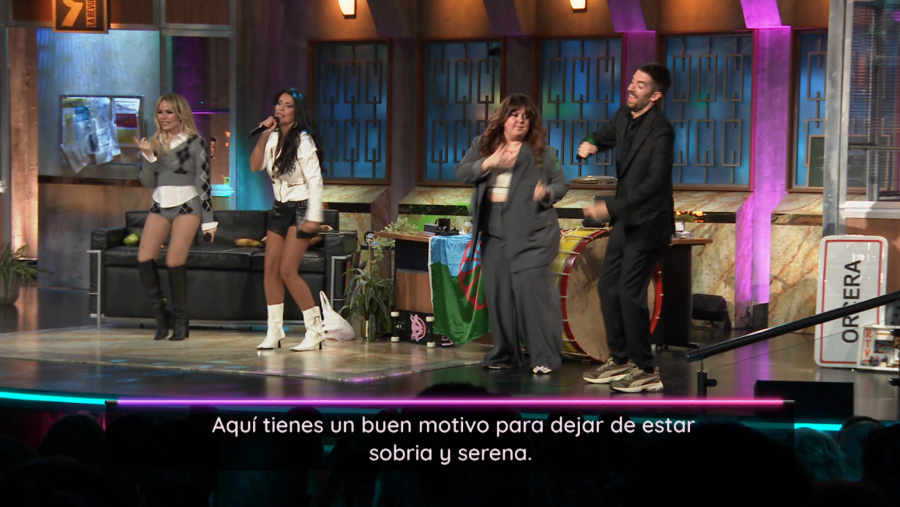 Escena con cuatro personas: dos mujeres, un hombre y una humorista, en un escenario con instrumentos musicales y un letrero de "Ópera".  Mensaje humorístico: "Aquí tienes un buen motivo para dejar de estar sobria y serena".
