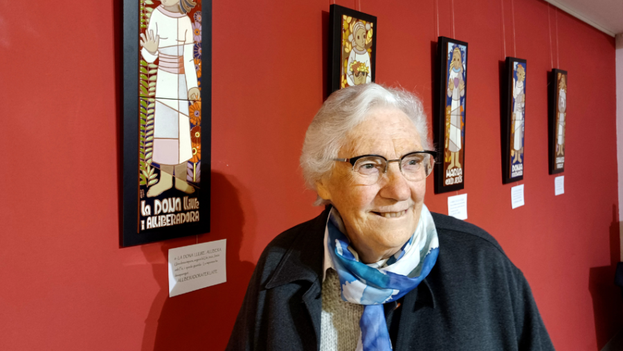 Regina Goberna sonríe junto a sus obras de arte: paneles con figuras estilizadas, posiblemente cerámicas, con una etiqueta que dice "La Down Lliure i Alliberadora".