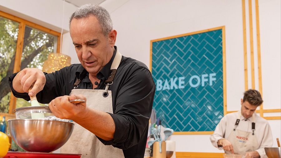 Víctor Sandobal, con delantal beige y camisa negra, mezcla ingredientes en un bol metálico durante su participación en "Bake Off".