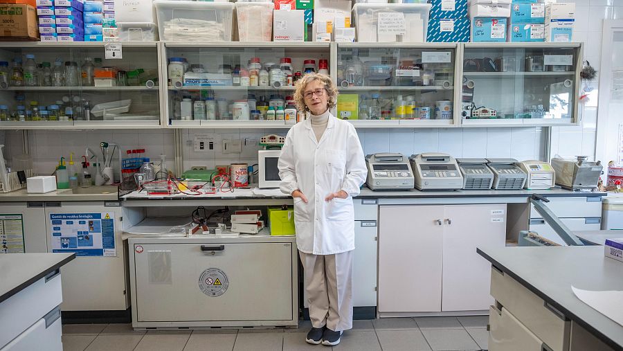 Genetista en su laboratorio, vestida con bata blanca, rodeada de material científico.  Imagen relacionada con investigaciones sobre ceguera hereditaria.