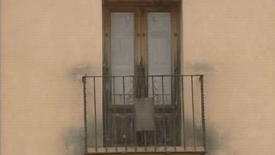 Daños por fuego en una ventana de madera con balcón, mostrando quemaduras en la pared.  Posible fallo en la ventilación.