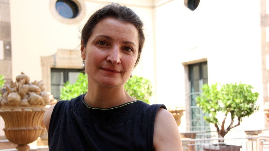 Retrato de Catherine Allard con blusa negra y pendientes, en un patio con arcos y macetas.  Aparece la palabra "Únics" debajo.