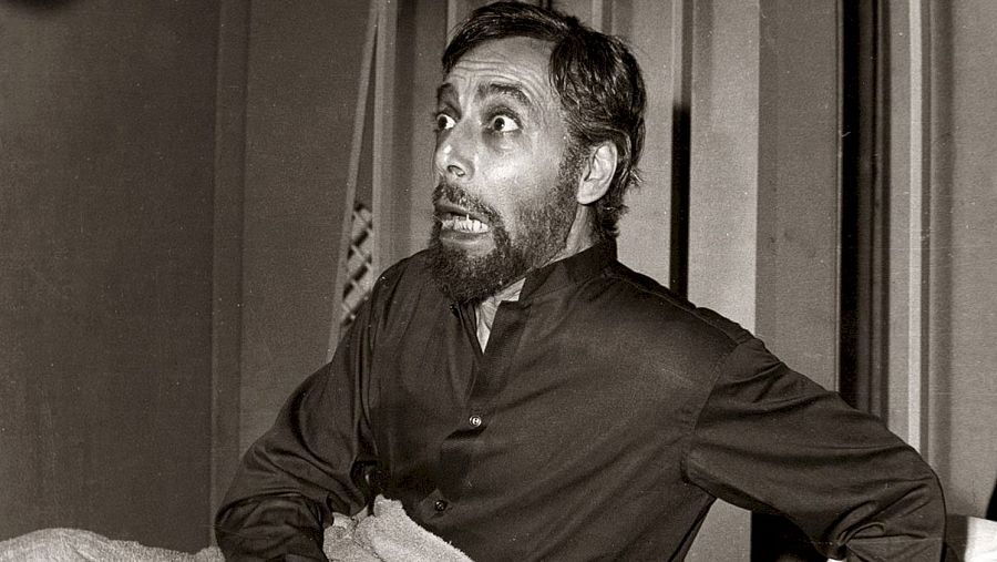 Narciso Ibáñez Menta, con expresión de terror, sentado en una escena de película o programa de TV.  Camisa oscura, fondo con paneles verticales.