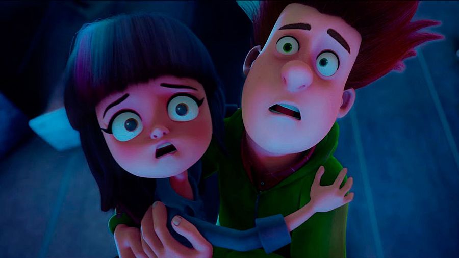 Dos niños, una niña de pelo oscuro y un chico pelirrojo, muestran expresiones de miedo en un fotograma de animación con fondo oscuro.