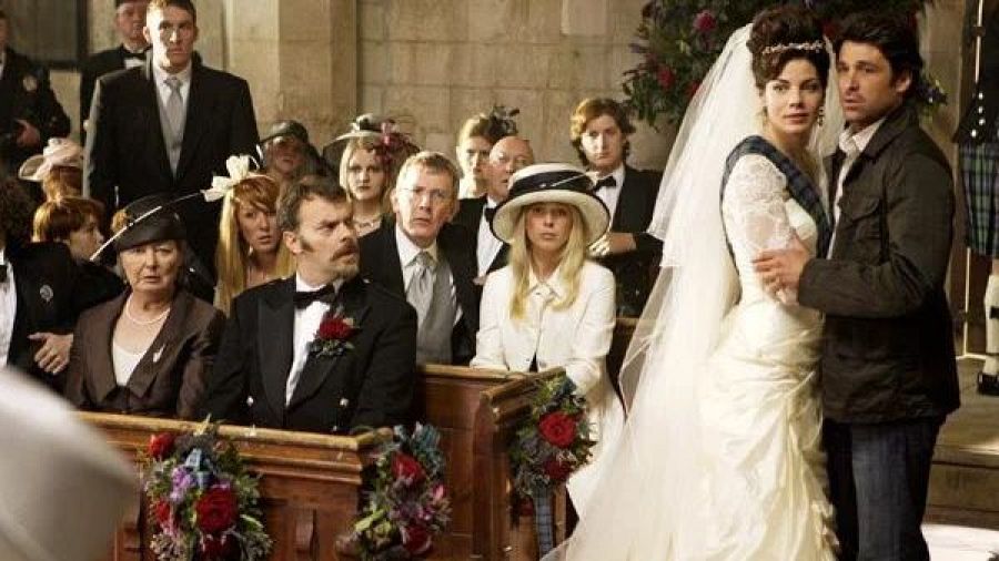 Boda en iglesia de piedra; novia con vestido blanco y tartán, novio con chaqueta oscura y vaqueros; invitados con ropa formal y tradicional escocesa.