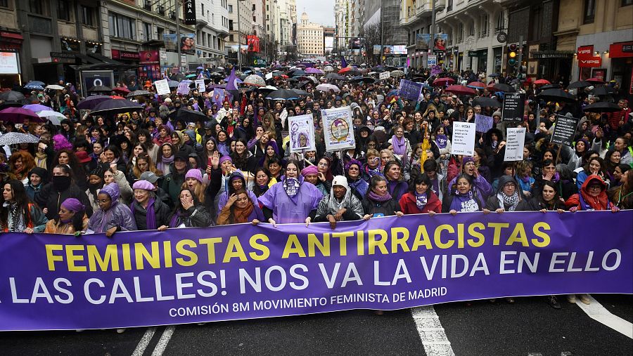 Multitudinaria manifestación feminista antirracista bajo la lluvia. Pancarta principal: "FEMINISTAS ANTIRRACISTAS A LAS CALLES! NOS VA LA VIDA EN ELLO".