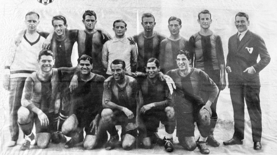Equipo de fútbol del FC Barcelona de 1928, campeones de Copa, fotografiados en blanco y negro. Once jugadores con uniforme, tres personas en ropa de calle. Dos filas de jugadores, algunos con brazos sobre hombros.