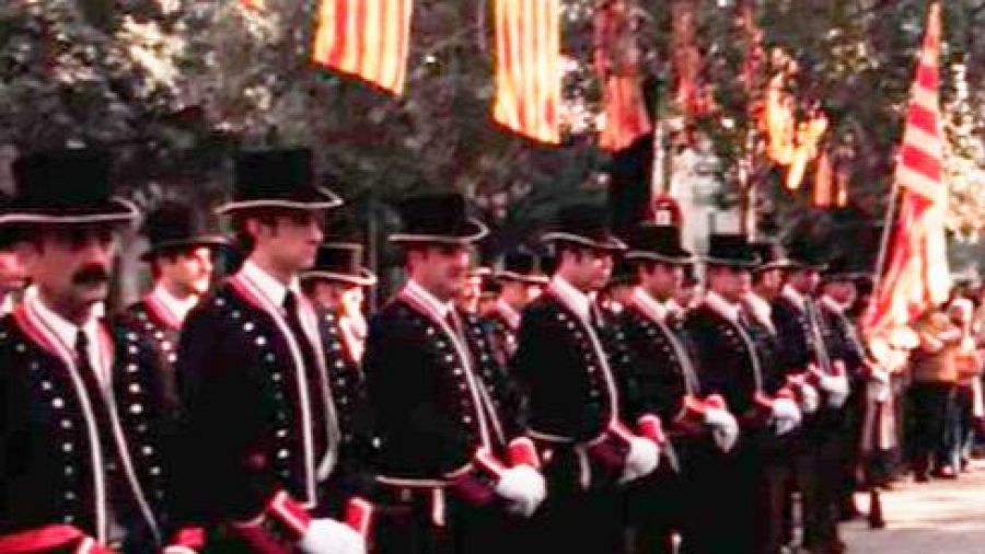 Mossos d'Esquadra en uniforme de gala participan en una ofrenda floral, con banderas catalanas al fondo.  Imagen histórica de la Diada de Catalunya.