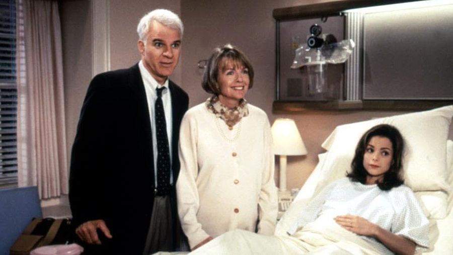 Steve Martin y Diane Keaton muestran preocupación junto a una paciente en bata de hospital.  Habitación con equipo médico visible. Escena de película.