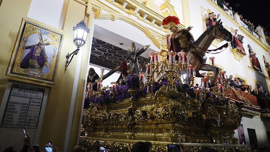 Imponente paso del Cristo de las Tres Caídas saliendo de la capilla, rodeado de velas y observado por la multitud.  Semana Santa en Sevilla.