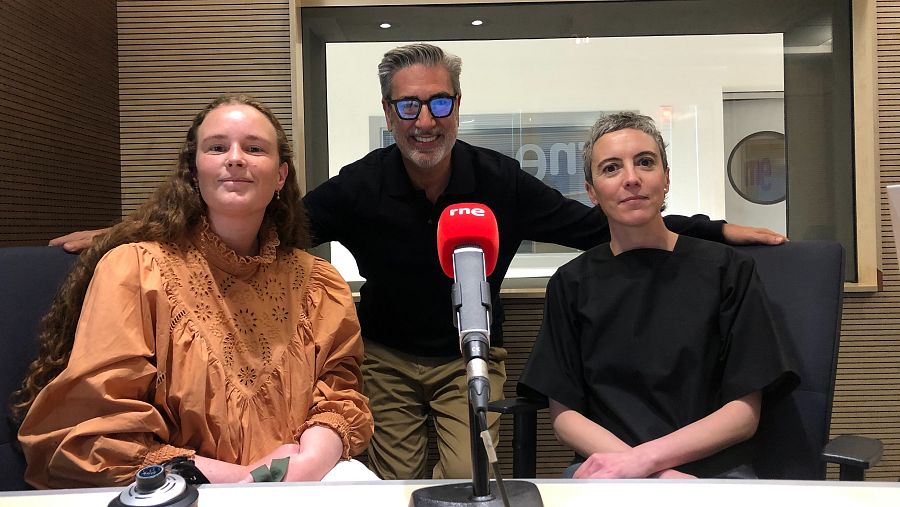 Entrevista en estudio de Radio Nacional de España. Tres personas, con vestimenta informal, sentadas alrededor de un micrófono con el logo de RNE visible, muestran una actitud amistosa.