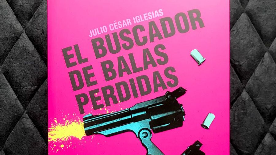 Portada rosa fucsia de libro con título "EL BUSCADOR DE BALAS PERDIDAS" en negro, mostrando un revólver disparando y casquillos de bala.