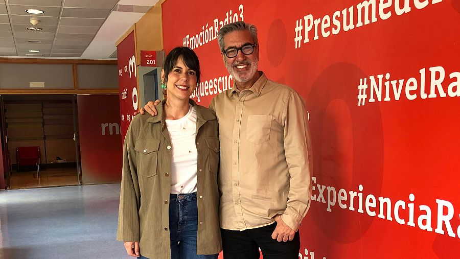 Noemí Martos y Arturo Martín sonríen en una foto tomada en Radio 3.  Se ven hashtags como #EmociónRadio3 y #NivelRadio3 en la pared.
