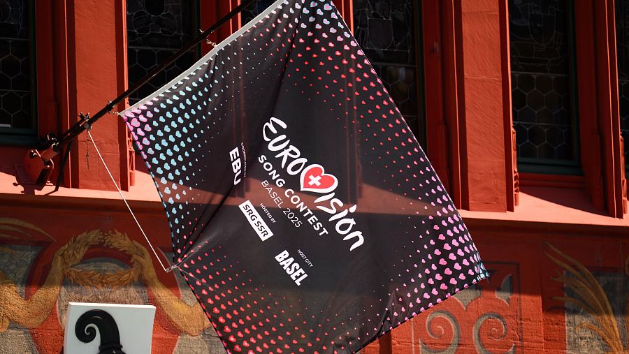 Bandera de Eurovisión 2025 en Basilea: diseño negro con corazones multicolores, logo de Eurovisión y texto 'Basel 2025'.