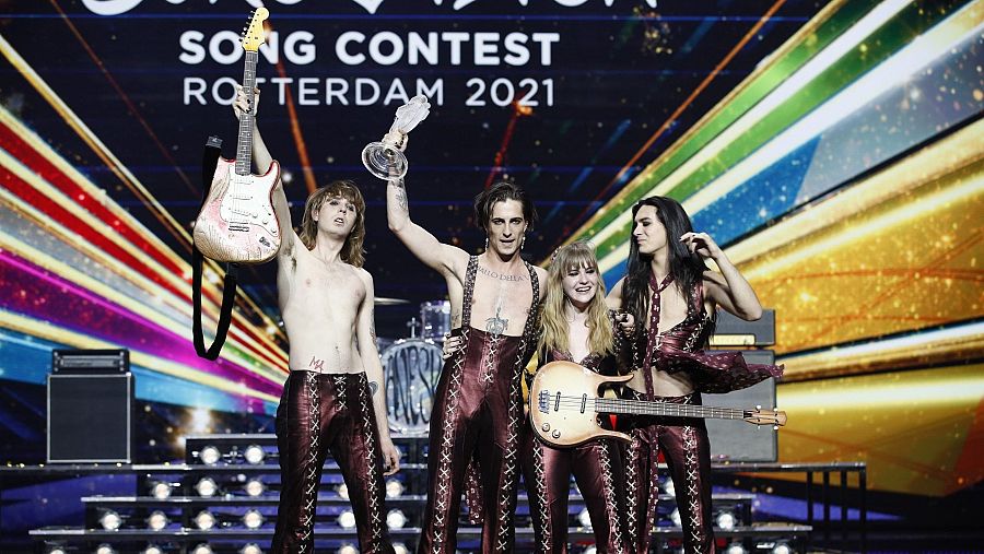 Måneskin celebra su triunfo en Eurovisión 2021, en Róterdam.  Miembros con trajes burdeos, uno con el trofeo y otro con guitarra.
