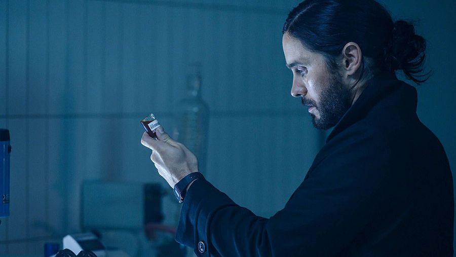 Jared Leto interpreta a Morbius en una escena de laboratorio, examinando una ampolla con líquido rojo.  Misterio y tensión.