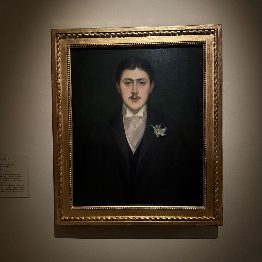 Retrato de un joven elegante con traje oscuro y flor blanca en la solapa, enmarcado en dorado. Pintado al óleo.