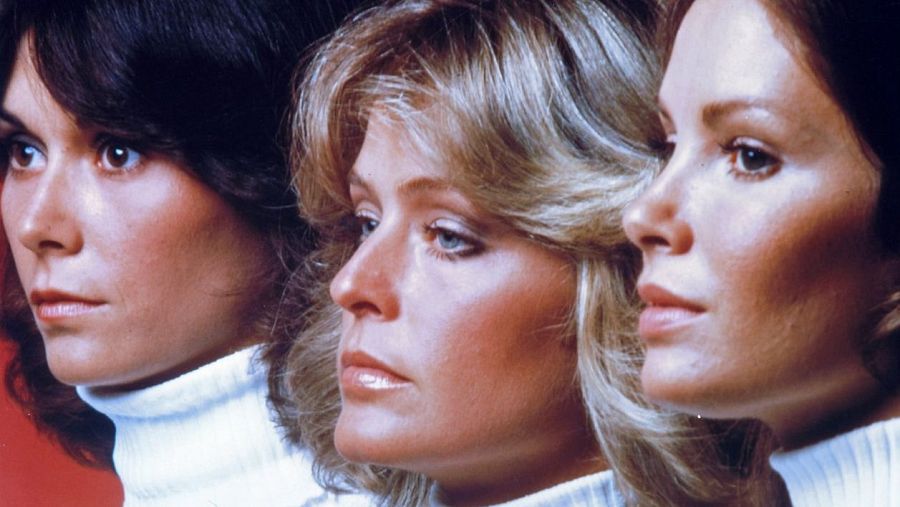 Tres actrices con jerseys blancos de cuello alto, de perfil y expresión seria. Imagen promocional de la serie "Los Ángeles de Charlie", que mostraba mujeres peleando con garra.