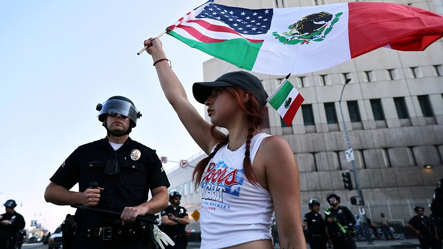 Una manifestante ondea una bandera junto a un policía en Los Ángeles