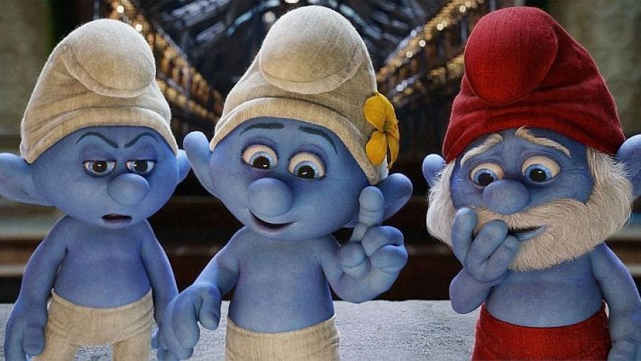 Tres Pitufos (Gruñón, Pitufina y Papá Pitufo) aparecen juntos en una escena interior.  Pitufina señala algo mientras Gruñón luce enfadado y Papá Pitufo parece pensativo.