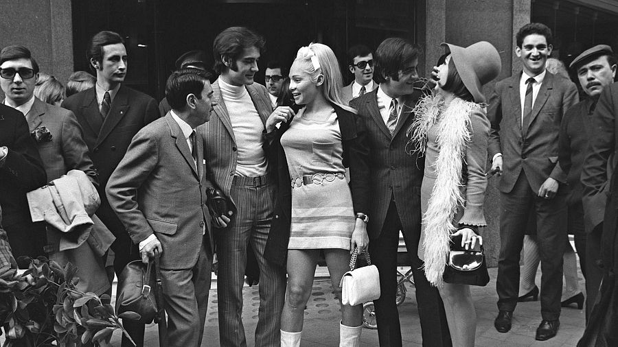 En 1968, el "Dúo Dinámico" regresaba deLondres tras ganar el primer premio del Festival de Eurovisión con su canción "La, La, La", interpretada por Massiel. En la foto, Ramón Arcusa (4º izq) y Manuel de la Calva (6º izq), miembros del "Dúo Dinámico", conversan con sus seguidores, entre los que se encuentra la ventrílocua y humorista Mari Carmen (dcha).