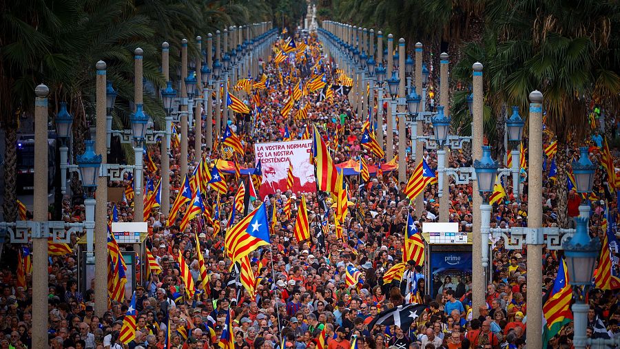 Manifestación multitudinaria en Barcelona con numerosas banderas independentistas catalanas y una pancarta que dice: "Vuestra normalidad es nuestra resistencia".