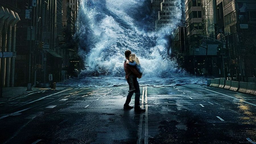 En una ciudad devastada por una inundación, un hombre carga a una niña, ambos luchando contra la fuerza de una enorme ola que amenaza con engullirlos. La escena muestra escombros y vehículos sumergidos, creando una atmósfera de caos y peligro.
