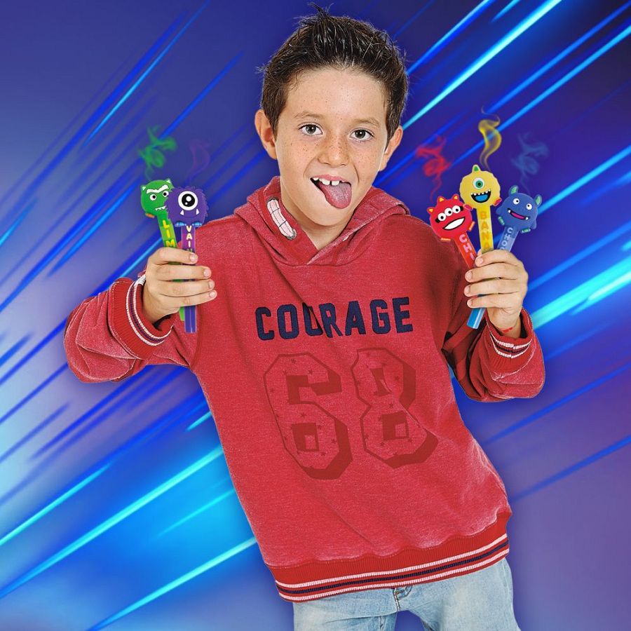 Un niño con pecas y una sudadera roja con la palabra "COURAGE" y el número "68" sonríe y saca la lengua, sosteniendo rotuladores con forma de monstruos que emiten humo de colores.