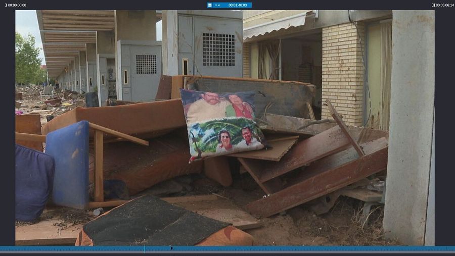 Una zona residencial devastada muestra escombros y muebles destrozados, incluyendo un cojín con fotografías. El entorno sugiere un desastre natural, transmitiendo una sensación de pérdida y desolación.