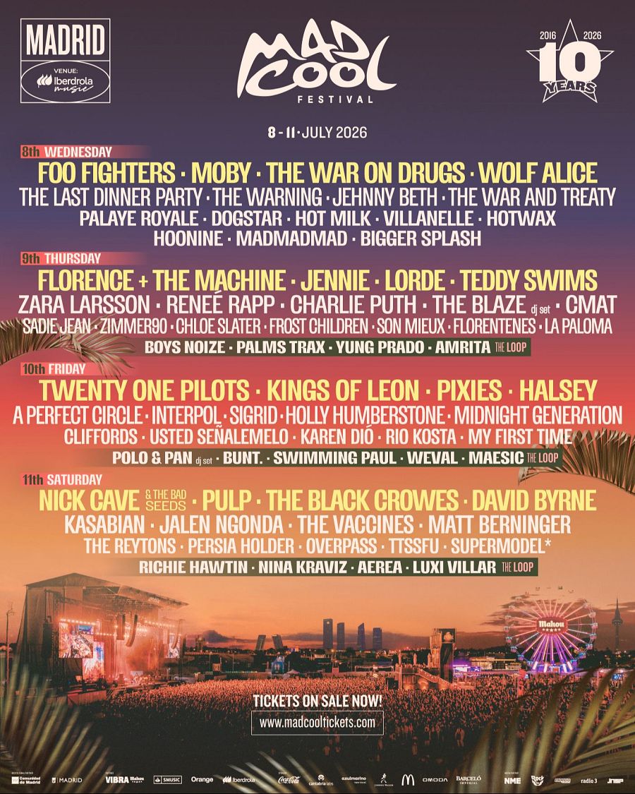 Un cartel publicitario anuncia un festival de música con múltiples artistas, con fechas del 8 al 11 de julio de 2026. Se observa una imagen de un escenario con público y una noria iluminada, con el horizonte de una ciudad al fondo.
