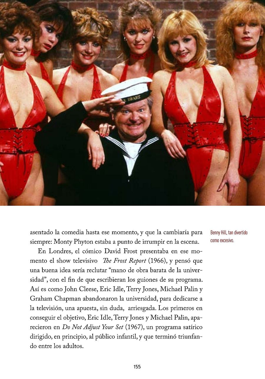 Benny Hill, vestido de marinero con un gorro, posa con varias mujeres en trajes de baño rojos. La imagen evoca el estilo cómico del artista, posiblemente relacionada con una sección de cultura.