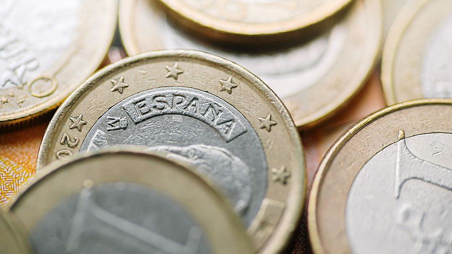 Primer plano de monedas de euro, con una moneda española que muestra la palabra "ESPAÑA" y estrellas, junto con el año "20" en otra moneda.