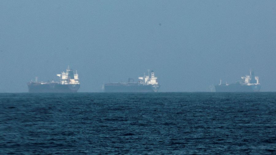 Tres buques cisterna oscuros navegan en el mar, alineados horizontalmente bajo un cielo nublado. El mar, en primer plano, presenta un color azul oscuro.