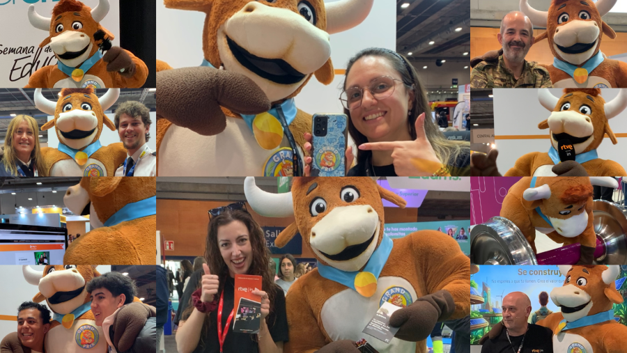 Maria Fernanda, la mascota de peluche con collarín azul y medallón dorado, posa con varias personas. Una mujer señala una funda de móvil con la imagen de la mascota, mientras que una chica sostiene un folleto.