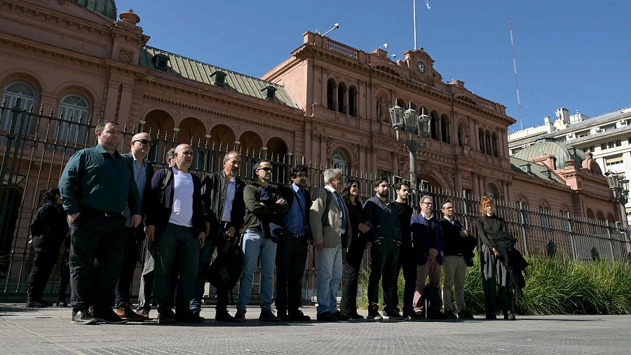 Periodistas posan frente a la Casa Rosada en Buenos Aires bajo un cielo azul, tras serles prohibido el acceso a las instalaciones gubernamentales.