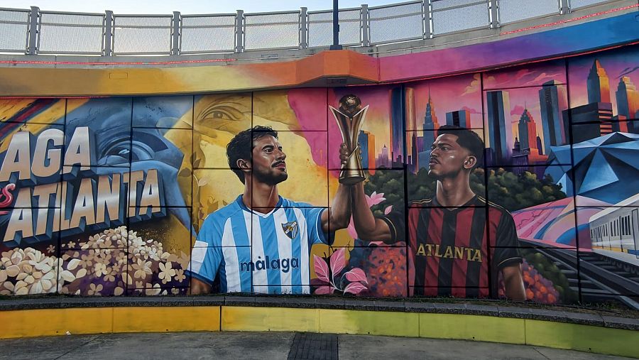Mural de hermandad Málaga-Atlanta con Luis Muñoz y otro jugador, trofeo, elementos culturales y urbanos. "MÁLAGA vs ATLANTA" preside la obra.