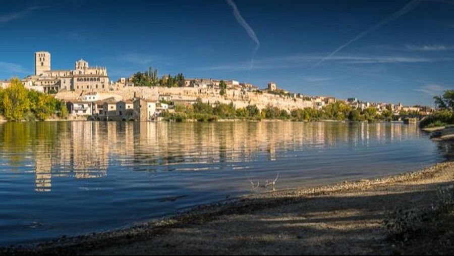 Vista panorámica de Zamora desde la orilla del río Duero, con la Catedral del Salvador y el casco histórico reflejados en las aguas.