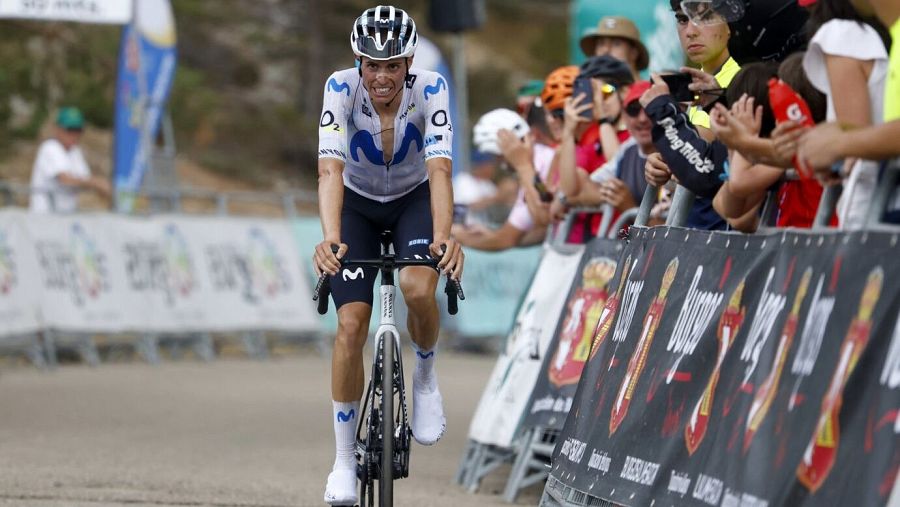 Enric Mas, ciclista del equipo Movistar, compite en la Vuelta a Burgos. Se observa su esfuerzo y la presencia de público y patrocinadores.