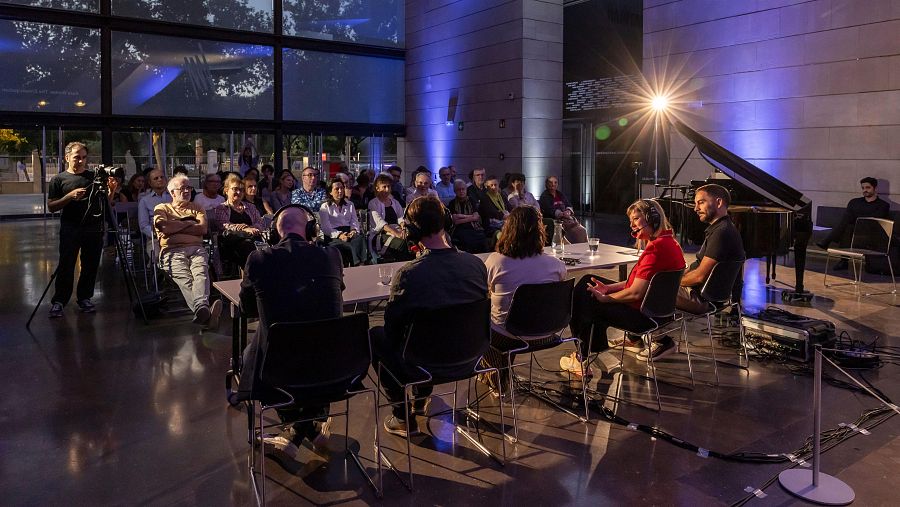 Evento en interiores con panel de discusión, audiencia y piano de cola. Grabación en vivo para Radio Clásica.