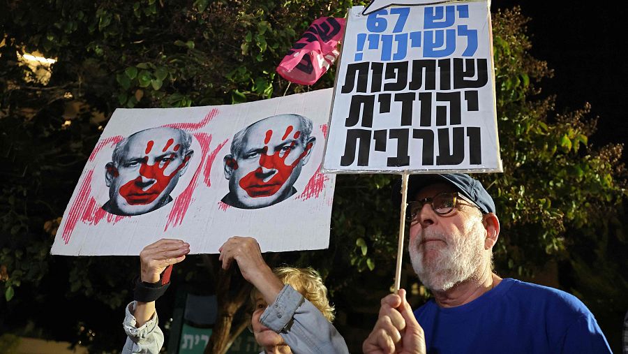 Activistas israelíes de izquierda sostienen pancartas durante una manifestación frente a la residencia de Gadi Eisenkot, líder del partido Yashar, para exigir la formación de un gobierno que incluya a partidos árabes