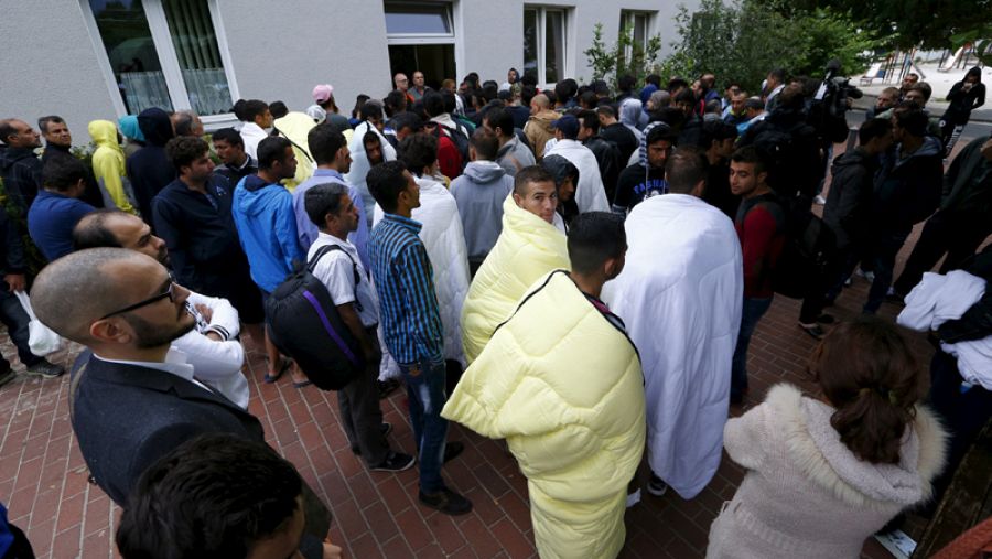 Migrantes y refugiados esperan a ser atendidos enfrente de la oficina de registro en el campo de refugiados de Friedland, Alemania
