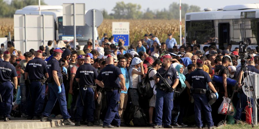 Policías húngaros vigilan a los migrantes que serán dirigidos en autobús desde la frontera croata hacia Beremend en Hungría