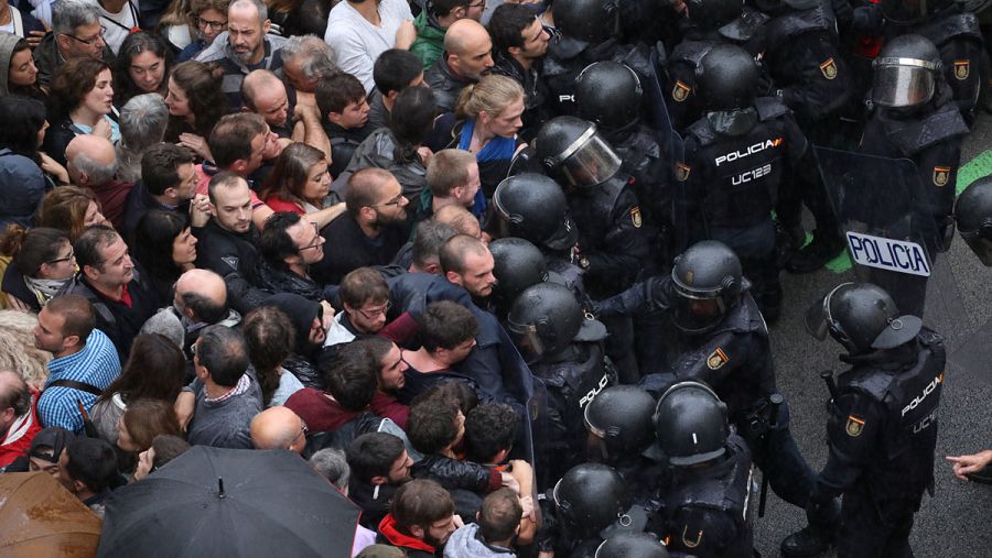 Los antidisturbios de la Policía Nacional bloquean la entrada de personas concentradas en el exterior de un colegio electoral en Barcelona