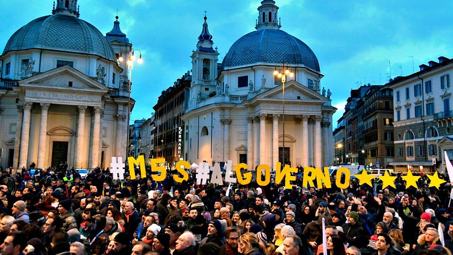 Los simpatizantes del Movimiento Cinco Estrellas asisten al acto de cierre de campaña de las elecciones generales en Roma, con un mensaje que reza: "M5S, al Gobierno"