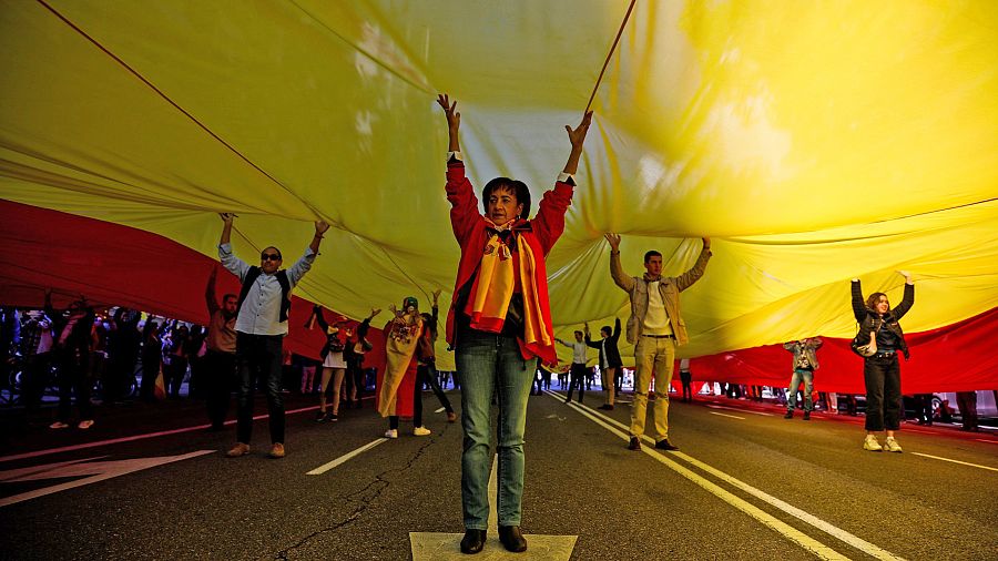 Decenas de personas sostienen una enorme bandera de España en el acto de Vox en la plaza de Colón