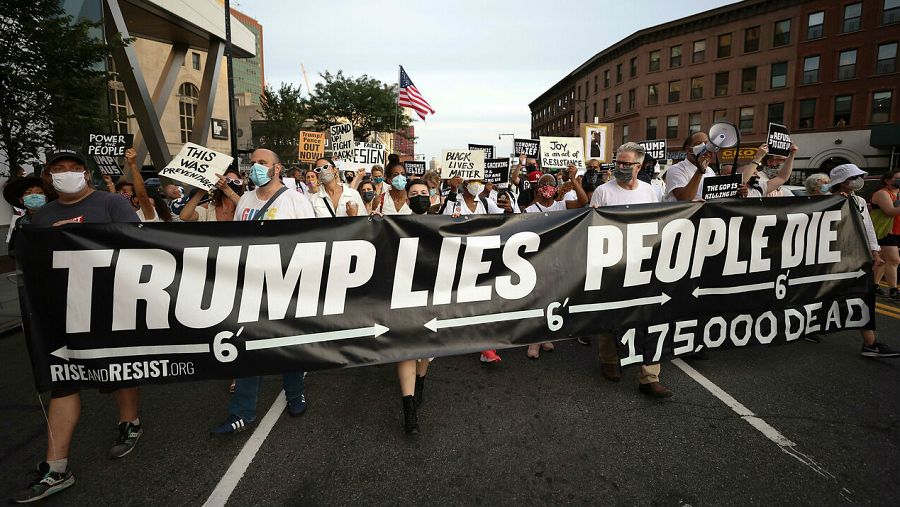 Las personas se reúnen para una vigilia y una 'Marcha por los Muertos' por las víctimas de la pandemia de coronavirus, en Brooklyn, Nueva York, EE. UU. con una pancarta que dice "Trump mienta, la gente muere".