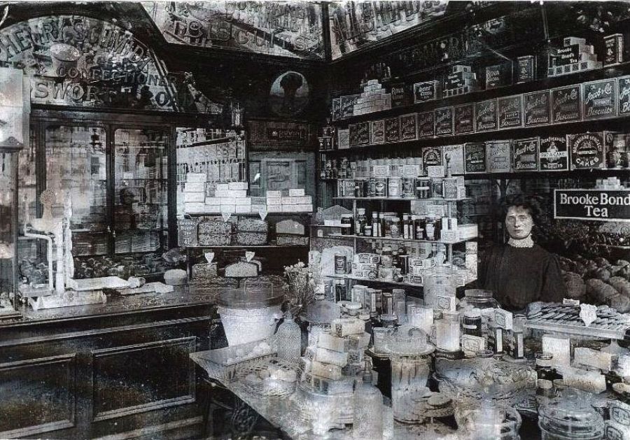 Dependienta posando en una tienda de alimentación victoriana.