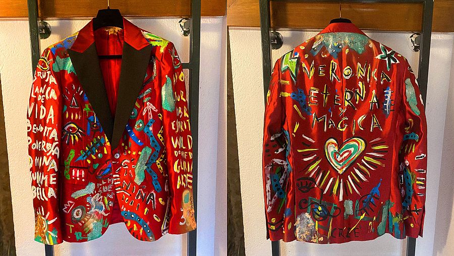 Chaqueta del esmoquin rojo que Aldo Comas ha llevado a los Goya 2022. Un homenaje a Verónica Forqué. El traje ha sido diseñado por Juan Avellaneda y pintado por el propio Comas. Se puede leer en la parte trasera: "Verónica eterna y mágica"