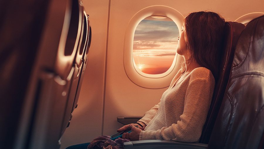 Pasajera de un avión mirando a través de la ventanilla de la aeronave